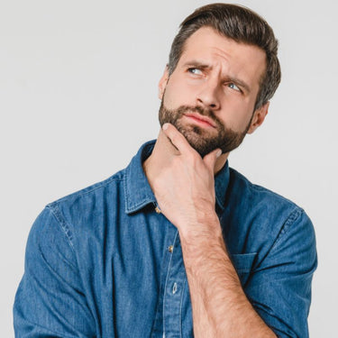 Man in a blue denim shirt with a thoughtful expression on a light gray background
