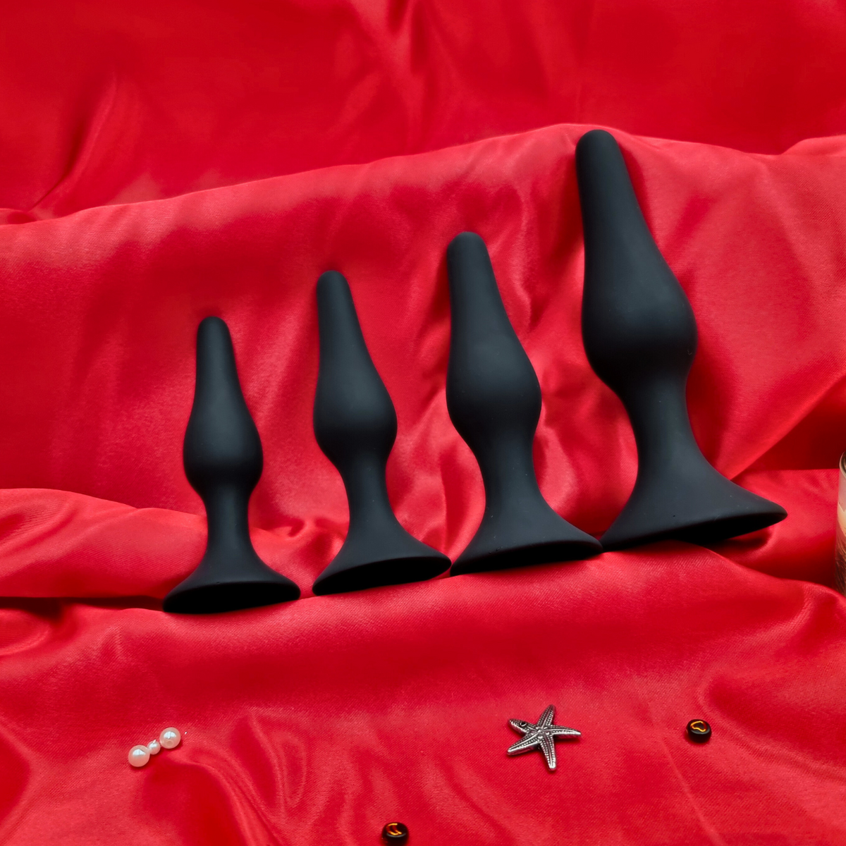 Luxurious black silicone butt plugs on red silk, perfect for beginners and advanced users alike.