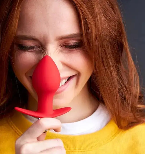 Red silicone sex toy with a curved tip and flared base, designed for pleasure.