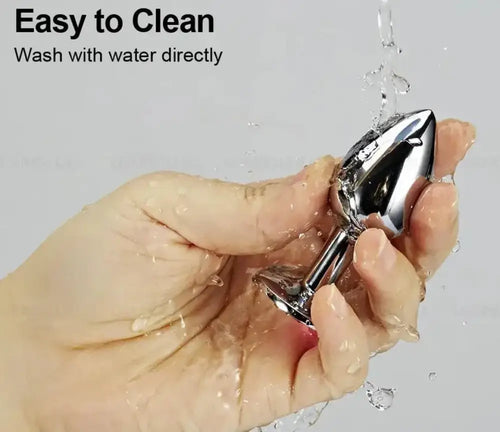 Hand holding the steel anal plug under running water, demonstrating easy cleaning and non-porous surface.
