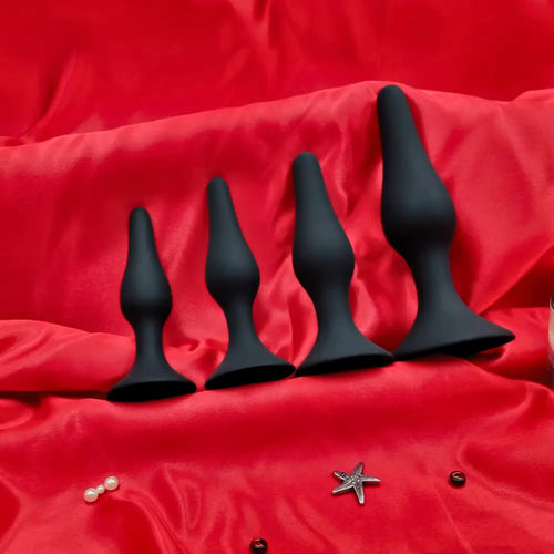 Side-by-side view of four silicone butt plugs, small to large, showing smooth matte finish and slim necks.
