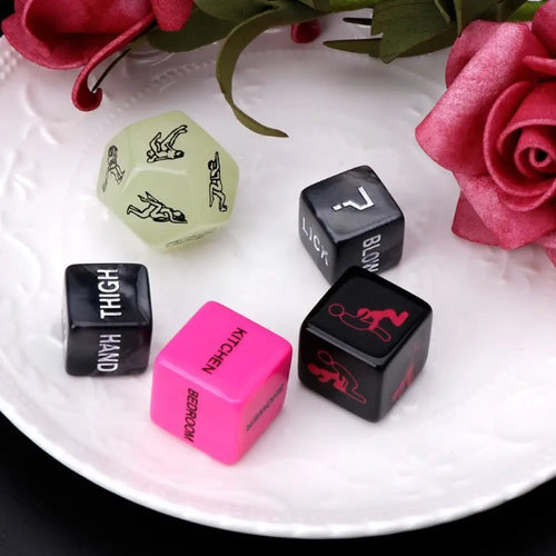 Close-up of pink, black, and green dice showing commands like kiss, bite, and spank.