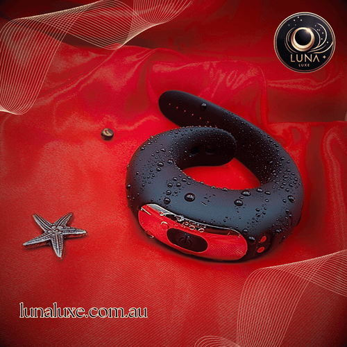 Black adjustable vibrating cock ring on red satin with water droplets, soft silicone strap design.
