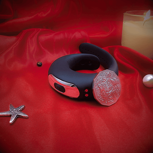 Cock ring with wireless remote on red background, magnetic USB charging port visible.