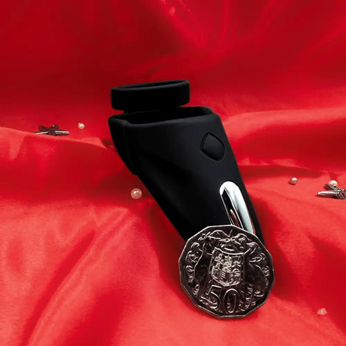 Rear angle of the vibrating cock ring sleeve on red background, showing charging port and textured underside.