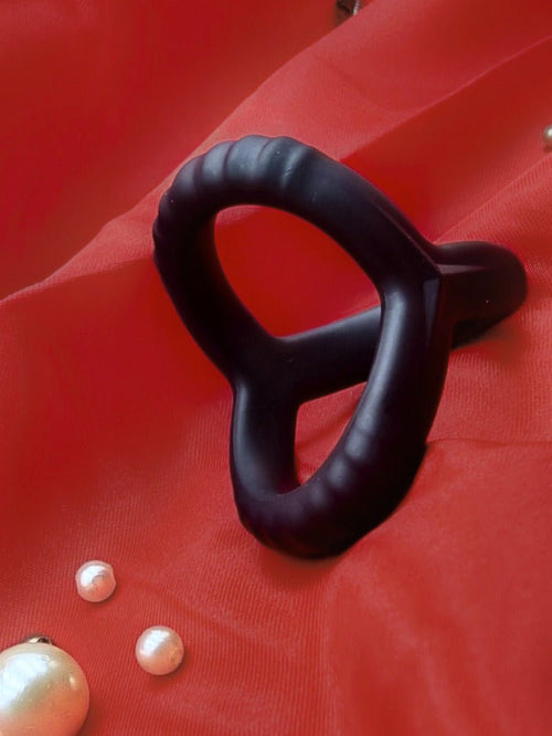 Close angle of the black silicone cock ring on red cloth, showing smooth matte finish and stretch.