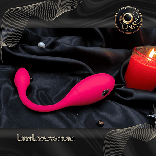 Magenta app-controlled wearable vibrator on black satin, U-shaped for internal and external stimulation.